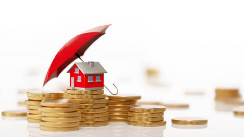 A toy umbrella on a toy house and coins