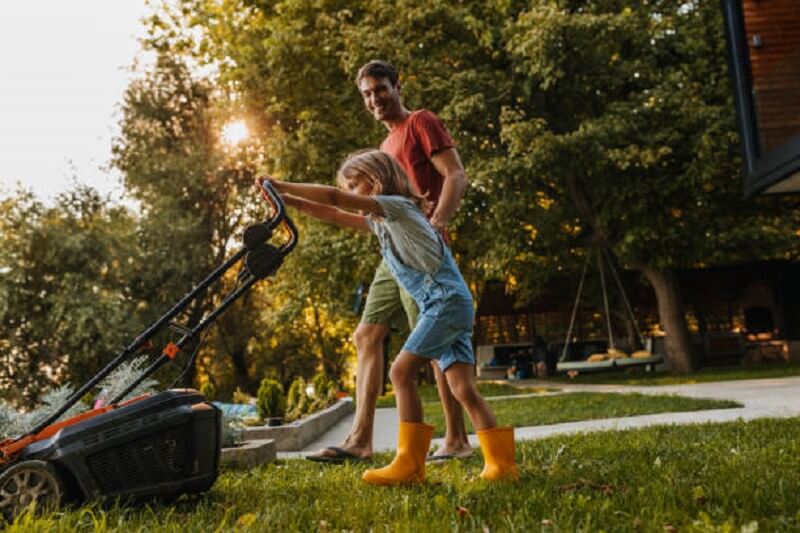 Man and little girl cutting the lawn grass